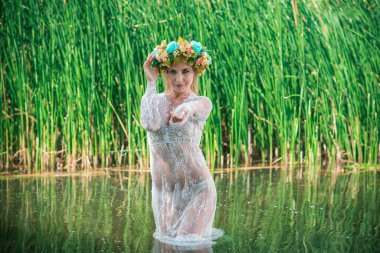 Uzun, beyaz dantelli bir elbise ve çelenk giymiş muhteşem bir göl perisi. Sanatsal fotoğrafçılık, gizemli sahne. Avrupalı cadı. Peri masalı