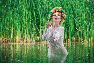 Uzun, beyaz dantelli bir elbise ve çelenk giymiş muhteşem bir göl perisi. Sanatsal fotoğrafçılık, gizemli sahne. Avrupalı cadı. Peri masalı