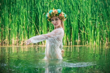 Uzun, beyaz dantelli bir elbise ve çelenk giymiş muhteşem bir göl perisi. Sanatsal fotoğrafçılık, gizemli sahne. Avrupalı cadı. Peri masalı