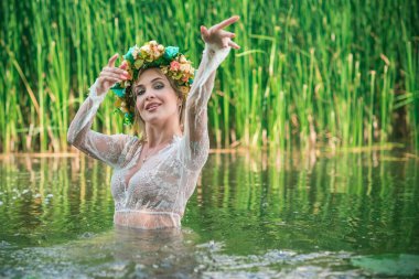 Uzun, beyaz dantelli bir elbise ve çelenk giymiş muhteşem bir göl perisi. Sanatsal fotoğrafçılık, gizemli sahne. Avrupalı cadı. Peri masalı