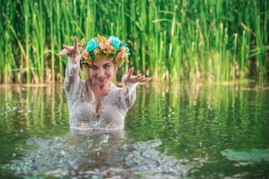 Uzun, beyaz dantelli bir elbise ve çelenk giymiş muhteşem bir göl perisi. Sanatsal fotoğrafçılık, gizemli sahne. Avrupalı cadı. Peri masalı