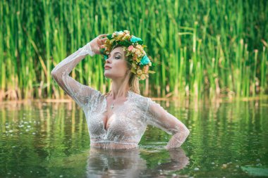 Uzun, beyaz dantelli bir elbise ve çelenk giymiş muhteşem bir göl perisi. Sanatsal fotoğrafçılık, gizemli sahne. Avrupalı cadı. Peri masalı
