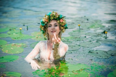 Uzun, beyaz dantelli bir elbise ve çelenk giymiş muhteşem bir göl perisi. Sanatsal fotoğrafçılık, gizemli sahne. Avrupalı cadı. Peri masalı