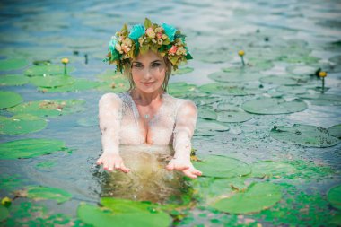 Uzun, beyaz dantelli bir elbise ve çelenk giymiş muhteşem bir göl perisi. Sanatsal fotoğrafçılık, gizemli sahne. Avrupalı cadı. Peri masalı