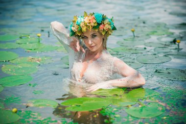 Uzun, beyaz dantelli bir elbise ve çelenk giymiş muhteşem bir göl perisi. Sanatsal fotoğrafçılık, gizemli sahne. Avrupalı cadı. Peri masalı