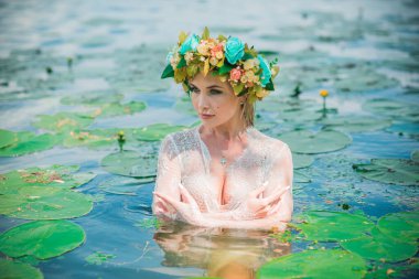 Uzun, beyaz dantelli bir elbise ve çelenk giymiş muhteşem bir göl perisi. Sanatsal fotoğrafçılık, gizemli sahne. Avrupalı cadı. Peri masalı