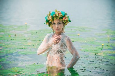 Uzun, beyaz dantelli bir elbise ve çelenk giymiş muhteşem bir göl perisi. Sanatsal fotoğrafçılık, gizemli sahne. Avrupalı cadı. Peri masalı