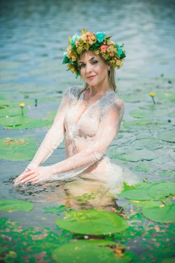 Uzun, beyaz dantelli bir elbise ve çelenk giymiş muhteşem bir göl perisi. Sanatsal fotoğrafçılık, gizemli sahne. Avrupalı cadı. Peri masalı