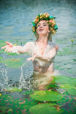 Uzun, beyaz dantelli bir elbise ve çelenk giymiş muhteşem bir göl perisi. Sanatsal fotoğrafçılık, gizemli sahne. Avrupalı cadı. Peri masalı