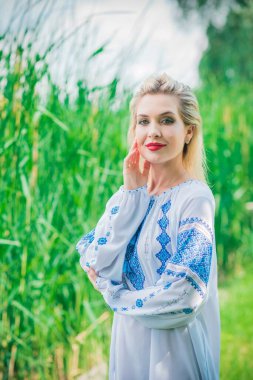 Etnik moda kavramı. Doğanın yerinde beyaz işlemeli gömlekli hoş bir kız.
