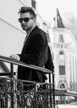 Yakışıklı genç adam eski kentte mavi kot, siyah ceket, beyaz gömlek, gözlük, şık saç, iyi ruh hali, güzel moda erkek arkadaş, vatandaş, güzel yüze sahip.