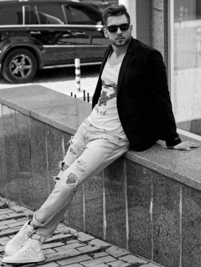 Yakışıklı genç adam eski kentte mavi kot, siyah ceket, beyaz gömlek, gözlük, şık saç, iyi ruh hali, güzel moda erkek arkadaş, vatandaş, güzel yüze sahip.