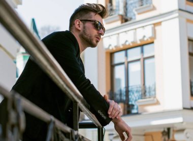 Yakışıklı genç adam eski kentte mavi kot, siyah ceket, beyaz gömlek, gözlük, şık saç, iyi ruh hali, güzel moda erkek arkadaş, vatandaş, güzel yüze sahip.