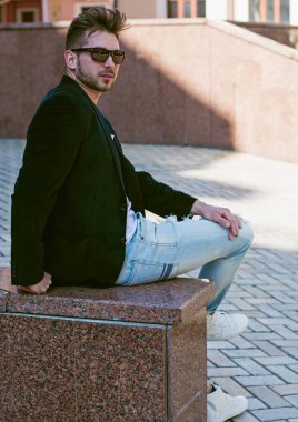 Yakışıklı genç adam eski kentte mavi kot, siyah ceket, beyaz gömlek, gözlük, şık saç, iyi ruh hali, güzel moda erkek arkadaş, vatandaş, güzel yüze sahip.