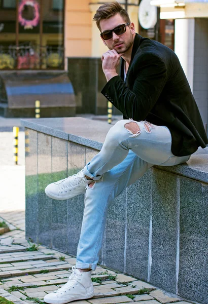 Yakışıklı genç adam eski kentte mavi kot, siyah ceket, beyaz gömlek, gözlük, şık saç, iyi ruh hali, güzel moda erkek arkadaş, vatandaş, güzel yüze sahip.