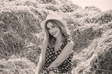 Country tarzı bir karışım, güzel kızıl saçlı bir kadın. Samanlıkta güzel bir bayanın portresi. Yeşil benekli elbiseli ve şapkalı kadın. Moda konsepti