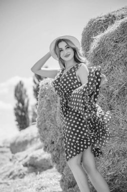 Country tarzı bir karışım, güzel kızıl saçlı bir kadın. Samanlıkta güzel bir bayanın portresi. Yeşil benekli elbiseli ve şapkalı kadın. Moda konsepti