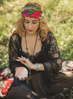 Çingene ruhu Tarot kartları, mumları ve sihirli topuyla tarlada, yaşam tarzında, öngörülerinde, Cadılar Bayramı 'nda kostüm için fikirleri olan Boho kadını.