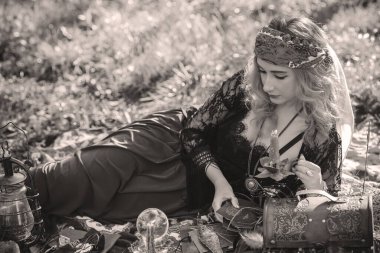 Çingene ruhu Tarot kartları, mumları ve sihirli topuyla tarlada, yaşam tarzında, öngörülerinde, Cadılar Bayramı 'nda kostüm için fikirleri olan Boho kadını.