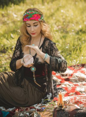Çingene ruhu Tarot kartları, mumları ve sihirli topuyla tarlada, yaşam tarzında, öngörülerinde, Cadılar Bayramı 'nda kostüm için fikirleri olan Boho kadını.