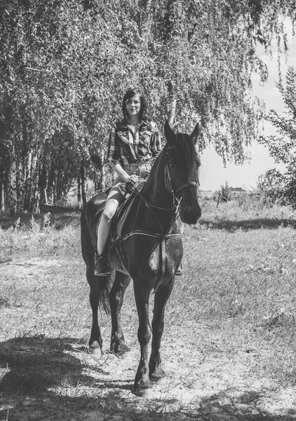 女人喜欢和马在一起年轻漂亮的女人穿着格子呢衬衫 外面穿着黑马 是美国乡村风尚的时髦姑娘 — 图库照片