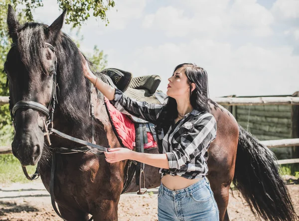 馬会社を楽しんでいる女性 若い美しい女性が黒馬の屋外で遊んだシャツを着て アメリカのカントリースタイルのスタイリッシュな女の子 — ストック写真