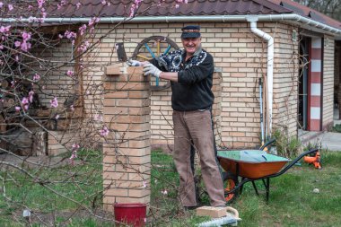 Yaşlı adam inşaat ve avluda çalışma hobisiyle meşgul..