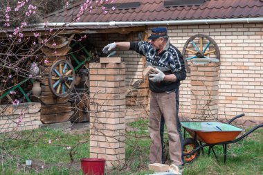 Yaşlı adam inşaat ve avluda çalışma hobisiyle meşgul..