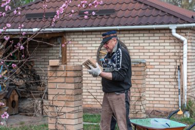 Yaşlı adam inşaat ve avluda çalışma hobisiyle meşgul..