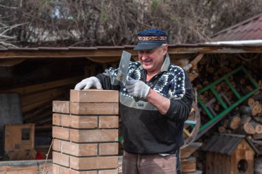 Yaşlı adam inşaat ve avluda çalışma hobisiyle meşgul..