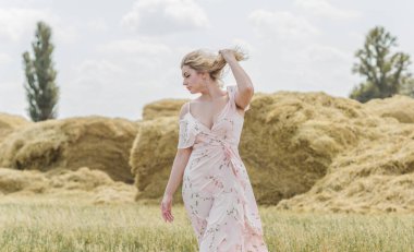 Country tarzı bir karışım, artı yumuşak pamuklu hafif elbiseli bir kadın. Samanlıktaki güzel bayanın portresi.
