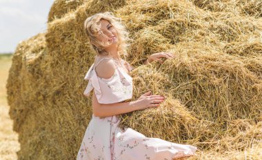 Country tarzı bir karışım, artı yumuşak pamuklu hafif elbiseli bir kadın. Samanlıktaki güzel bayanın portresi.