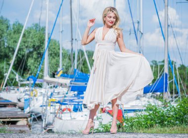 Yat kulübündeki güzel sarışın bayan. Açık havada uçan ipek beyaz elbiseli kadın, dinlenme zamanı.