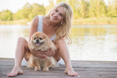 Köpeğiyle gölde gezen hoş sarışın kadın, evcil hayvanlara karşı sevgi kavramı. İnsanlarla ve hayvanlarla dostluk