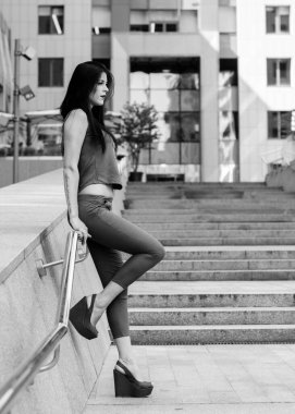 Koyu renk uzun saçlı mavi takım elbiseli bir kadın şehirde arkadaşlarını bekliyor. Büyük bir metropolün ve vatandaşların yaşam tarzı.