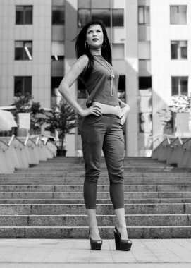 Koyu renk uzun saçlı mavi takım elbiseli bir kadın şehirde arkadaşlarını bekliyor. Büyük bir metropolün ve vatandaşların yaşam tarzı.