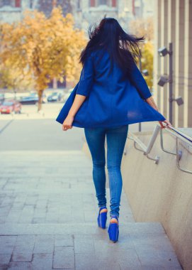 Koyu renk uzun saçlı mavi takım elbiseli bir kadın şehirde arkadaşlarını bekliyor. Büyük bir metropolün ve vatandaşların yaşam tarzı.