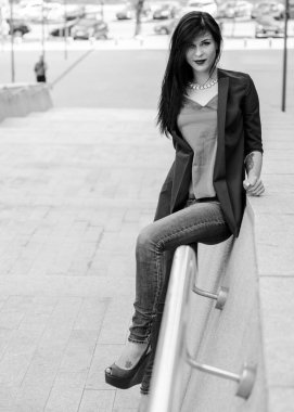 Koyu renk uzun saçlı mavi takım elbiseli bir kadın şehirde arkadaşlarını bekliyor. Büyük bir metropolün ve vatandaşların yaşam tarzı.