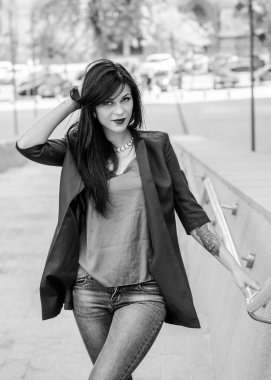 Koyu renk uzun saçlı mavi takım elbiseli bir kadın şehirde arkadaşlarını bekliyor. Büyük bir metropolün ve vatandaşların yaşam tarzı.