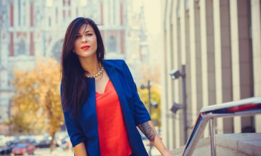 Koyu renk uzun saçlı mavi takım elbiseli bir kadın şehirde arkadaşlarını bekliyor. Büyük bir metropolün ve vatandaşların yaşam tarzı.