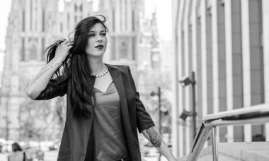 Koyu renk uzun saçlı mavi takım elbiseli bir kadın şehirde arkadaşlarını bekliyor. Büyük bir metropolün ve vatandaşların yaşam tarzı.