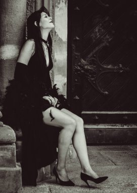 Cadılar Bayramı 'nda gotik ve görkemli retro görünümlü bir bayan. Tüyleri ve el yapımı güzel aksesuarları olan klasik elbiseli güzel bir vatandaş. Cadılar Bayramı için fikirler