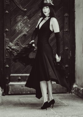 Cadılar Bayramı 'nda gotik ve görkemli retro görünümlü bir bayan. Tüyleri ve el yapımı güzel aksesuarları olan klasik elbiseli güzel bir vatandaş. Cadılar Bayramı için fikirler