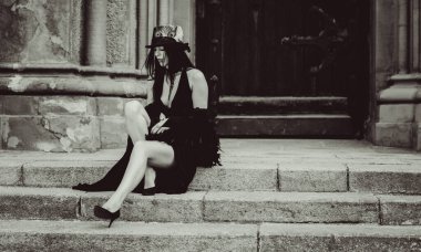 Cadılar Bayramı 'nda gotik ve görkemli retro görünümlü bir bayan. Tüyleri ve el yapımı güzel aksesuarları olan klasik elbiseli güzel bir vatandaş. Cadılar Bayramı için fikirler