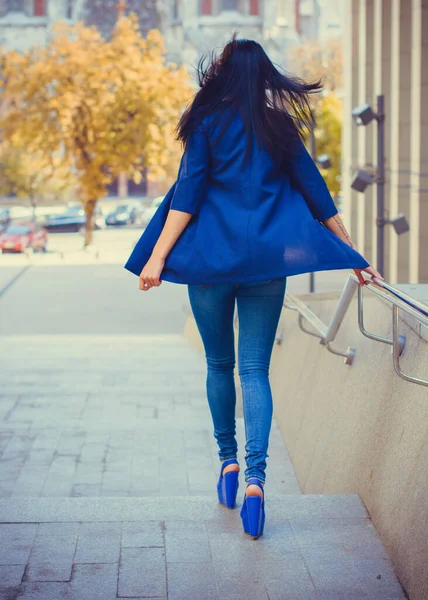 Koyu renk uzun saçlı mavi takım elbiseli bir kadın şehirde arkadaşlarını bekliyor. Büyük bir metropolün ve vatandaşların yaşam tarzı.