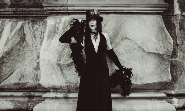 Gothic lady in a luxurious glamorous retro look for Halloween. Beautiful citizen in vintage clothing with feathers and fine accessories of handmade work. Ideas for the Halloween holiday