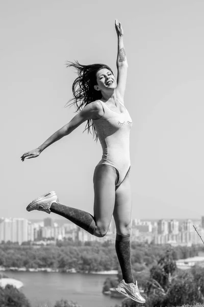 Exercises at city park. Lady exercising outdoors. Concept of healthy lifestyle. Portrait of athletic young woman resting on a nature. Beautiful woman at the park on a sunny day.