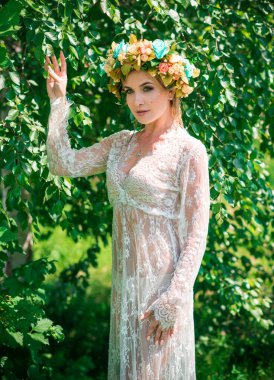 Çiçek çemberli, saçlı, dantelli, gölde şeffaf elbiseli romantik bir kadın.