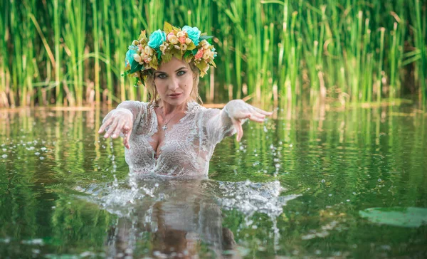 一个浪漫的女人在花圈里 在头发上 花边透明的衣服在湖里 — 图库照片
