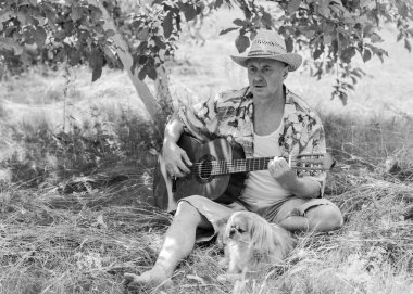 Basılı tişörtlü komik yaşlı adam gitar çalıyor ve doğada şarkı söylüyor, Amerika 'ya seyahat ediyor ve tatil için zevk alıyor.